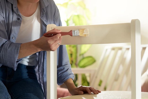 Foto frau malt stuhl mit einem pinsel im wohnzimmer