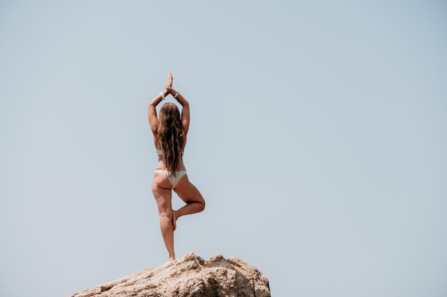 Frau Meer Yoga Rückansicht der freien ruhigen Glückseligkeit zufriedene Frau mit langen Haaren, die auf einem Felsen steht