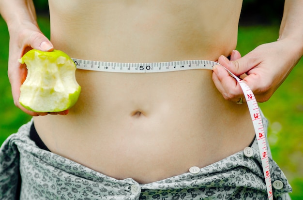 Foto frau messen ihren bauch und halten grünen apfel in der hand