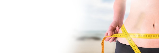 Frau misst Gewicht mit Maßband an der Taille am Sommerstrand mit Übergang