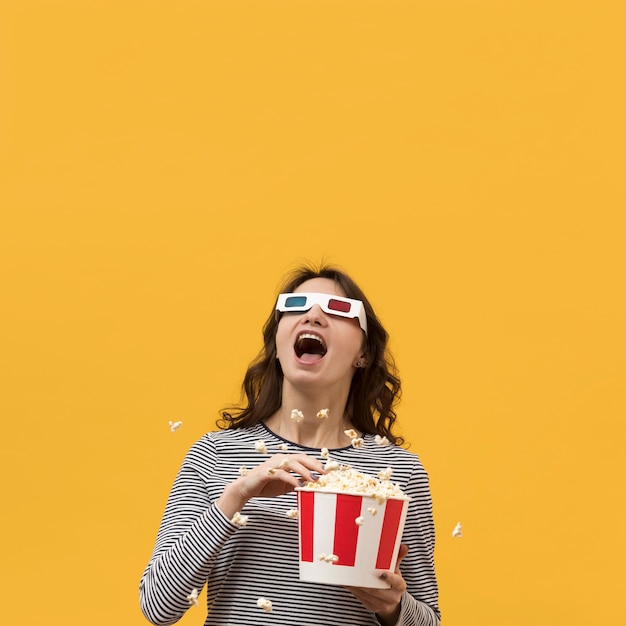 Frau mit 3d Gläsern, die einen Eimer mit Popcorn halten