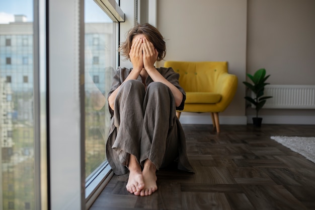 Frau mit Angst sitzt auf der Vorderansicht des Bodens