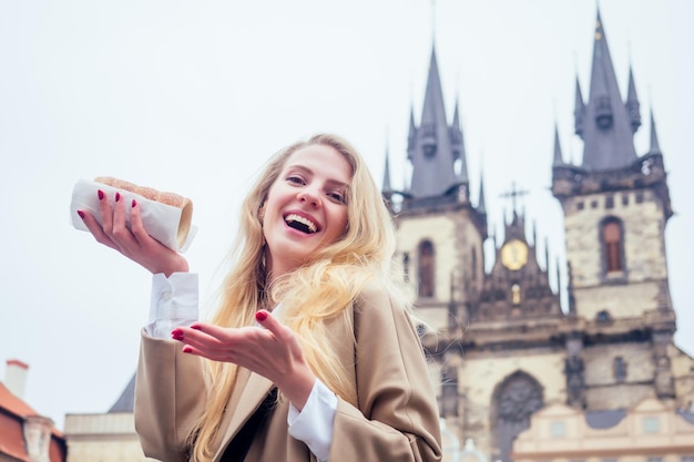 Foto frau mit appetit isst einen traditionellen tschechischen süßen trdelnik auf dem prager altstädter ring