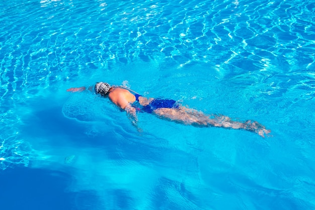 Frau mit Badeanzug, die auf einem blauen Wasserbecken schwimmt.