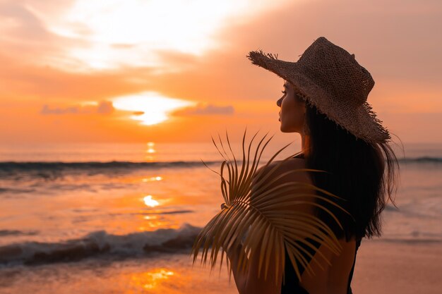 Frau mit Badeanzug und Hut am Strand