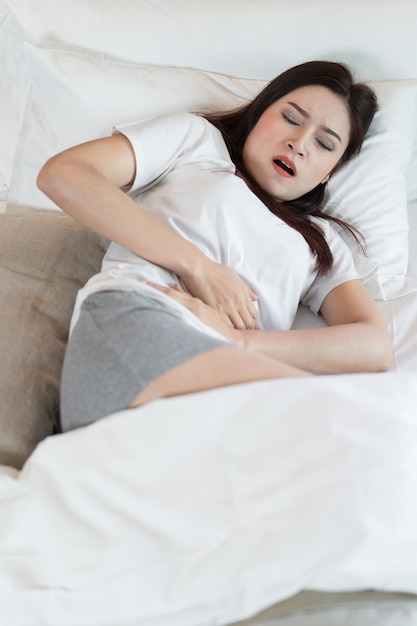 Frau mit Bauchschmerzen im Bett