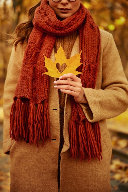 Frau mit Blatt mit herzförmigem Loch hinter der Brust im Freien. Herbstsaison und Liebeskonzept