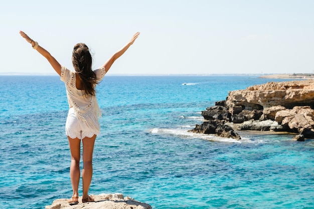 Frau mit Blick auf die atemberaubende Aussicht vom berühmten Aussichtspunkt Cape Greco, während sie am Rand einer Klippe steht