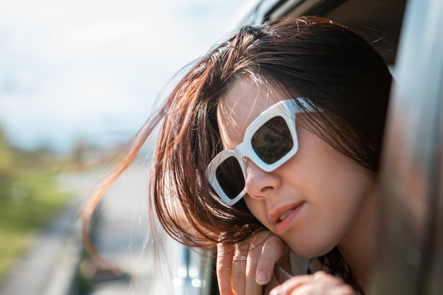 Frau mit Blick aus dem Autofenster Road Trip Reisekonzept sonnigen Sommertag