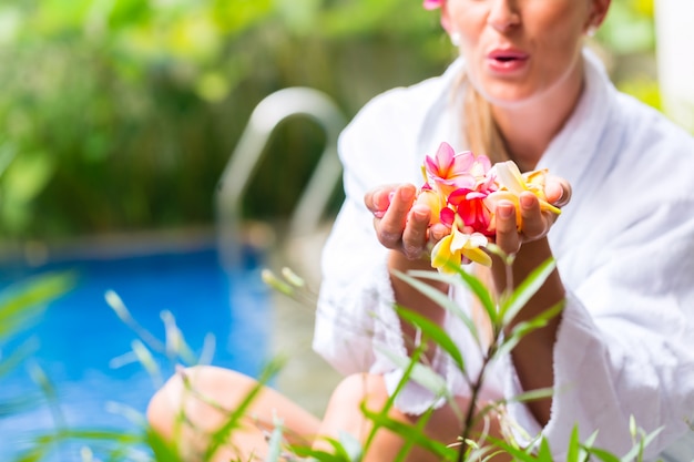 Frau mit Blumen am tropischen Pool