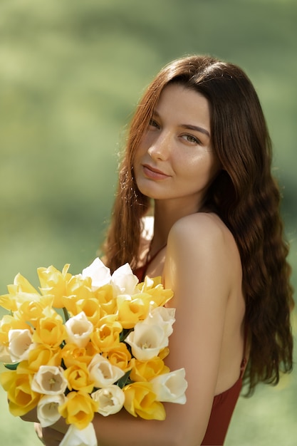 Frau mit Blumenstrauß der Frühlingsblumen im Freien