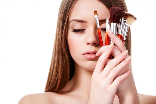 Frau mit braunem Haar hält Satz von Make-up-Bürsten