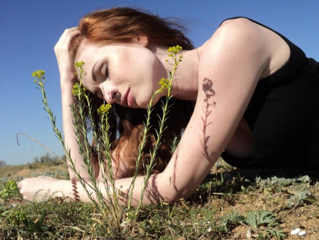 Foto frau mit braunen haaren sitzt an einem sonnigen tag auf dem feld