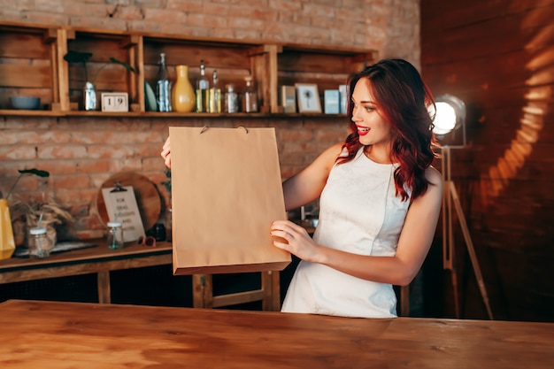 Frau mit brauner klarer Papierbasteltasche auf der Küche