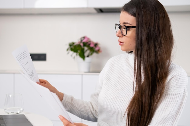 Frau mit Brille arbeitet mit Dokumenten und plant Ausgaben