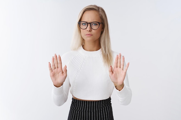 Frau mit Brille und abgeschnittenem Pullover, die die Handflächen in Stop and No hebt