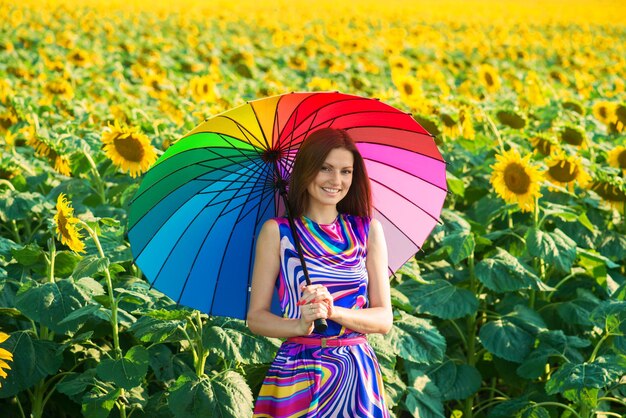 Frau mit buntem Regenschirm in den Sonnenblumenfeldern