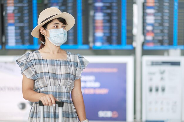 Frau mit chirurgischer Gesichtsmaske am Flughafen