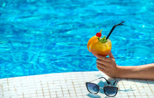 Frau mit Cocktail am Pool. Selektiver Fokus.