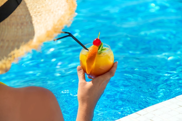 Frau mit Cocktail am Pool. Selektiver Fokus.