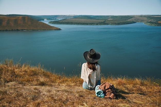 Frau mit Cowboyhut sitzt auf einem Berggipfel in der Nähe von Dnister