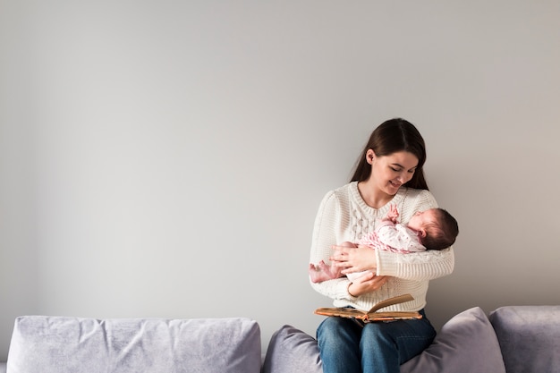 Frau mit dem Buch, das kleines Baby hält