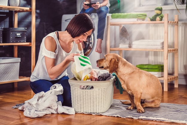 Frau mit dem Hund, der Kleidung auf dem Boden sortiert