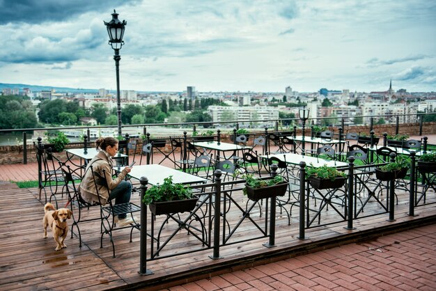 Frau mit dem Hund in der leeren Caféterrasse