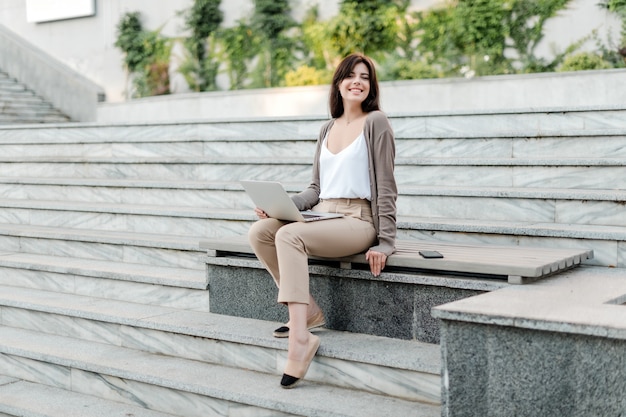 Frau mit dem Laptop im Freien auf der Treppe