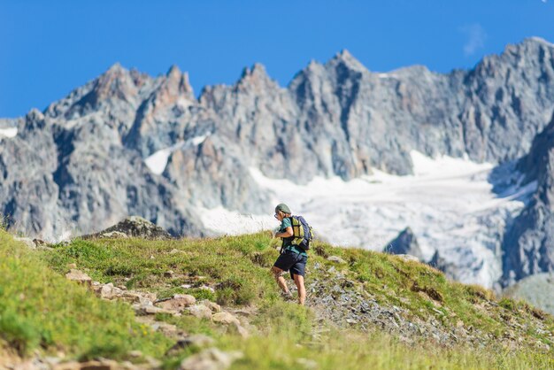 Frau mit dem Rucksack, der auf Berg, landschaftlich reizvollem Gletscher und dramatischer Landschaftssommer-Fitness-Wohlbefinden-Rückansicht, Freiheitskonzept wandert