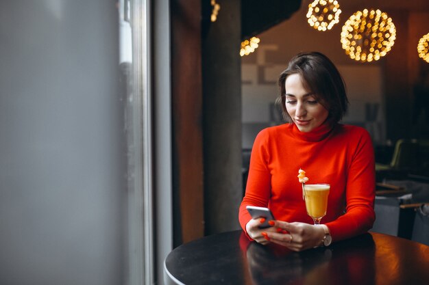 Frau mit dem Telefon, das in einem Café sitzt