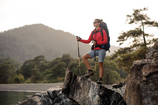 Frau mit dem Wandern der Ausrüstung geht durch steinige Küste