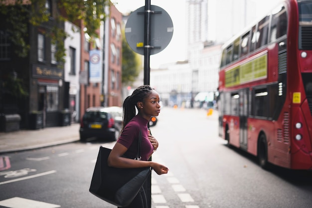 Frau mit den Borten, die eine Straße in im Stadtzentrum gelegenem London kreuzen