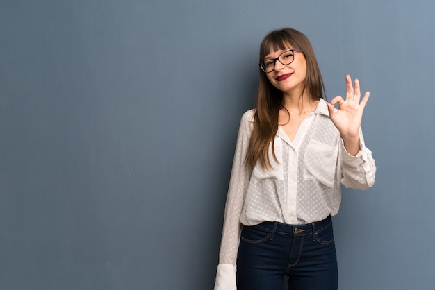 Frau mit den Gläsern, die ein okayzeichen mit den Fingern zeigen