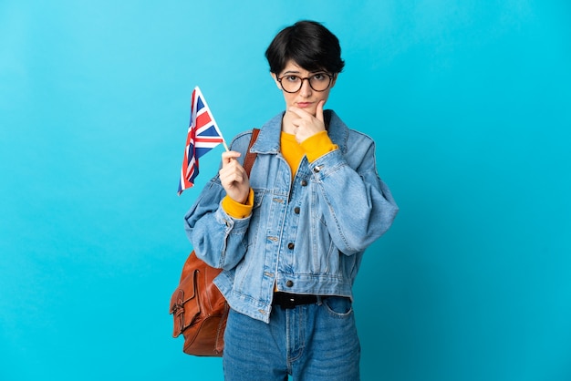 Frau mit den kurzen Haaren, die eine Flagge des Vereinigten Königreichs lokalisiert auf blauem Denken halten