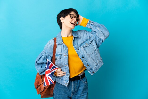 Frau mit den kurzen Haaren, die eine Großbritannienflagge halten, die viel lächelnd isoliert