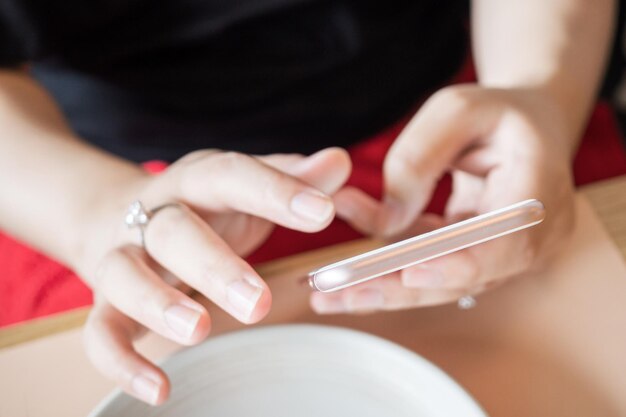 Frau mit Diamantring zur Hand mit Smartphone im Café-Restaurant