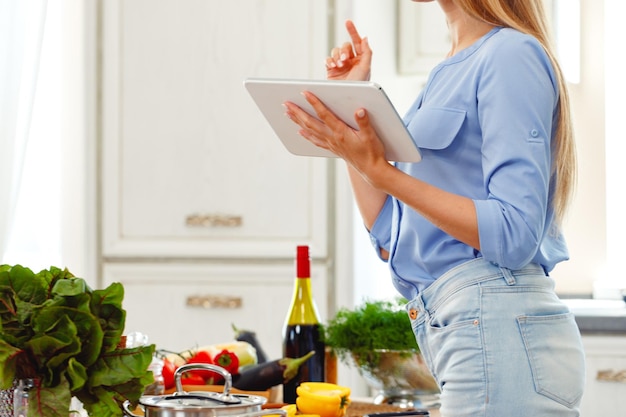 Foto frau mit digital-tablette beim kochen in der küche