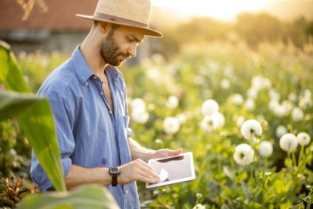 Frau mit digitalem Tablet auf Blumenfarm im Freien