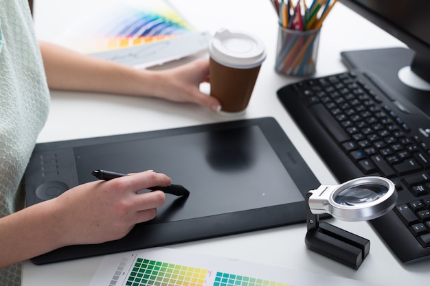 Frau mit digitalem Tablet mit Tasse Kaffee auf weißem Tischhintergrund