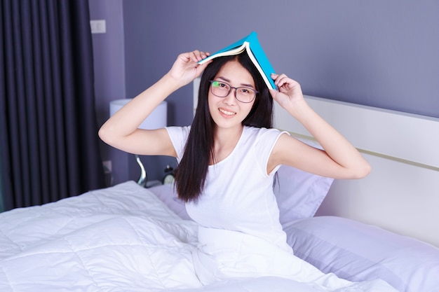 Frau mit einem Buch auf dem Bett im Schlafzimmer zu Hause