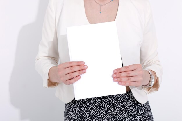 Foto frau mit einem buchmagazin und laptop auf einem weißen hintergrund studenten-geschäfts-mockup