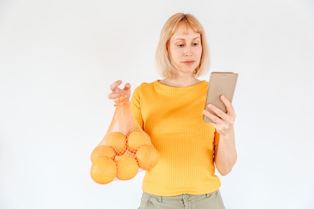 Frau mit einem Bündel Orangen und einem Smartphone auf weißem Hintergrund