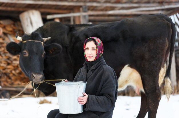 Frau mit einem Eimer zum Melken von Kühen im Winter