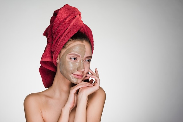 Frau mit einem Handtuch auf dem Kopf trägt eine Reinigungsmaske auf ihr Gesicht auf