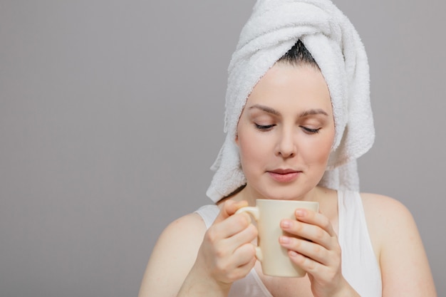 Foto frau mit einem handtuch auf dem kopf und einer tasse