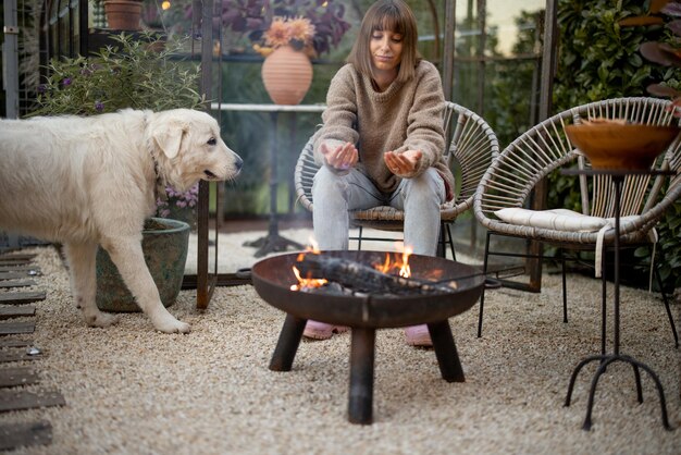 Frau mit einem Hund am Feuer im Hinterhof