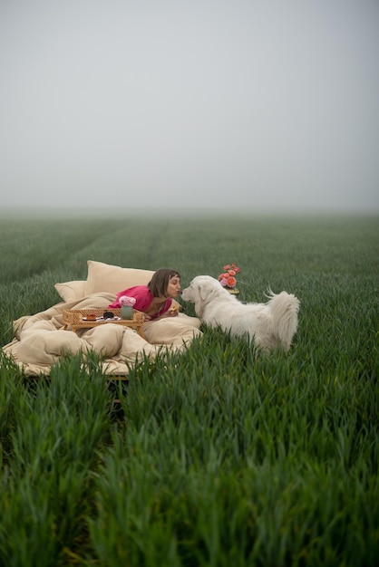 Frau mit einem Hund auf dem Bett auf einem grünen Feld im Freien