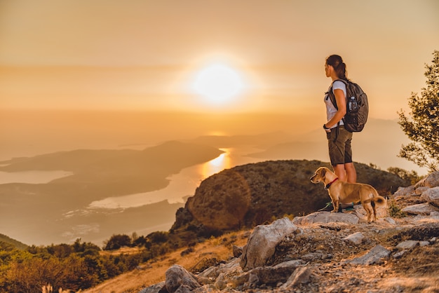 Frau mit einem Hund auf einem Berggipfel