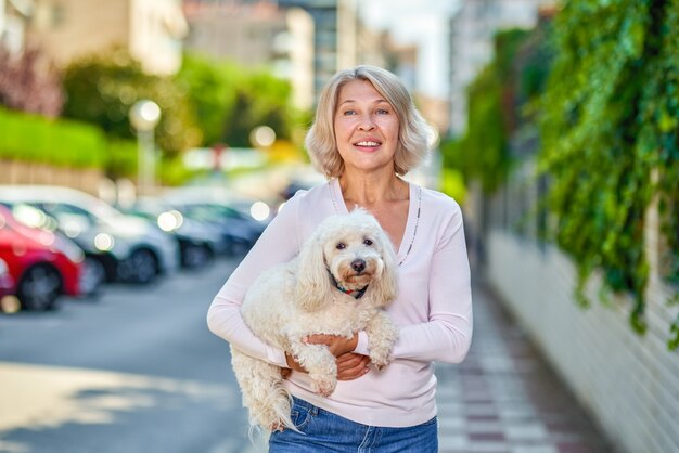 Frau mit einem Hund im Arm auf einer Stadtstraße